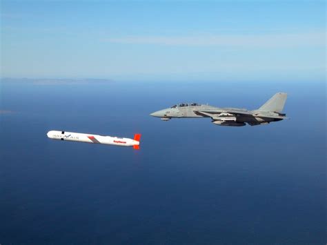 A Tactical “Tomahawk” Block IV cruise missile is escorted by a Navy F-14 Tomcat fighter during a ...