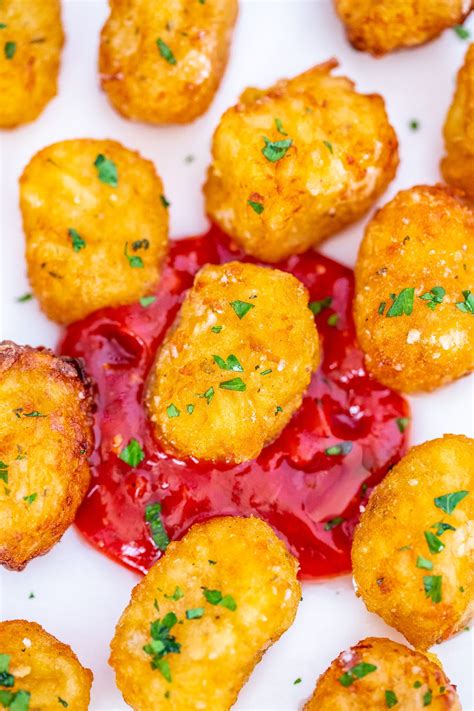 some fried food on a white plate with ketchup and green garnish