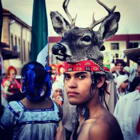 a man wearing a deer's headdress with other people in the background