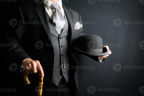 Man in Dark Gray Suit Holding Bowler Hat and Umbrella on Black Background. Vintage Style and ...