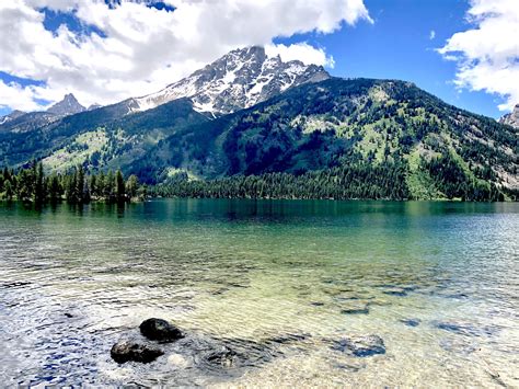 there is a mountain range in the distance with water and rocks on the foreground