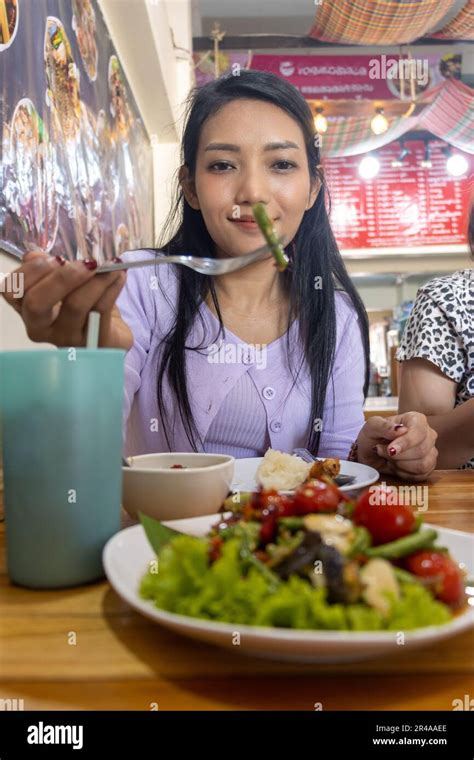 A young woman eating a yard long bean salad in a Thai restaurant Stock Photo - Alamy