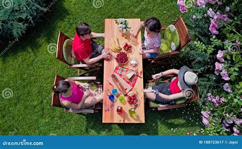 Family and Friends Eating Together Outdoors on Summer Garden Party. Aerial View of Table with ...