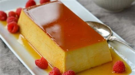 a piece of cake on a white plate with raspberries and caramel sauce