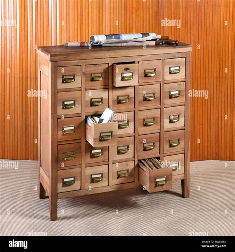 Wooden archive cabinet for storage with rows of small drawers with brass handles and labels, two ...