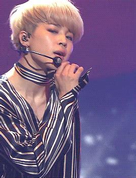 a woman with blonde hair wearing a black and white striped shirt holding a microphone to her mouth