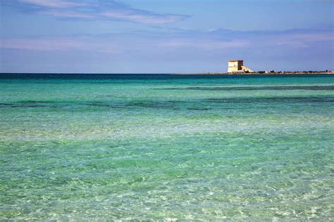 the ocean is blue and green with small white buildings in the distance ...