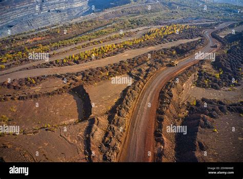 Huge mounds of waste iron ore near the quarry. Belaz trucks driving in mining factory, mine ...