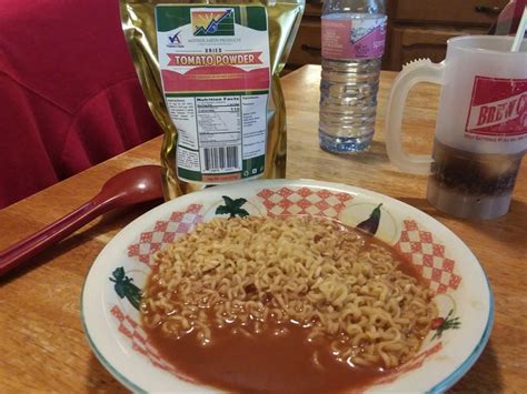 a plate of noodles with sauce on it next to a bag of soup and a fork