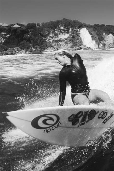 a woman in a wet suit riding a wave on a surfboard