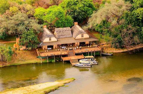 an aerial view of a house on the water with two boats parked in front of it