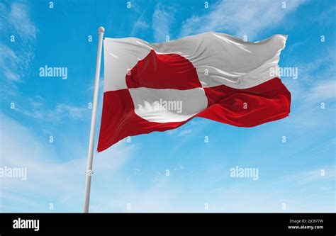 official flag of Greenland , Denmark at cloudy sky background on sunset ...