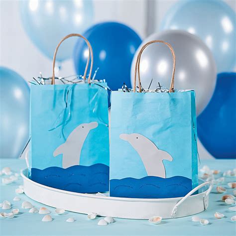 two paper bags with dolphins on them sitting in front of balloons