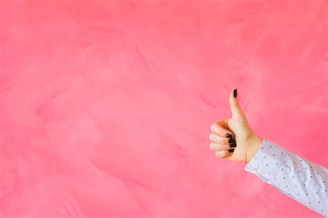 Premium Photo | Person showing thumbs up hand gesture on empty pink background