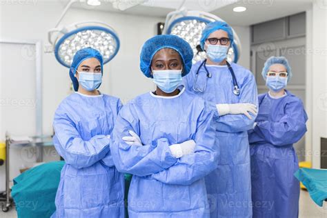 Group of medical surgeons wearing hospital scrubs in operating theatre. Portrait of successful ...