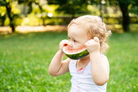 Funny Smiling Kid Boy in White Bodysuit Eating Watermelon at Green Lawn ...