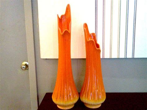two orange vases sitting next to each other on a table in front of a mirror