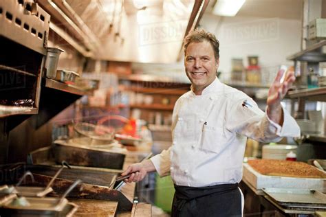 Portrait of Caucasian chef waving in restaurant kitchen - Stock Photo - Dissolve