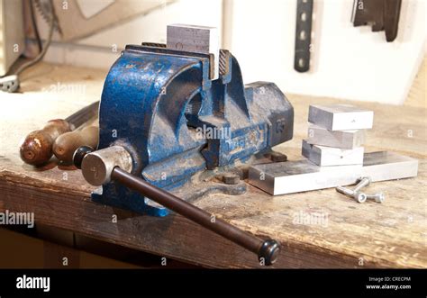 Vice with a block of metal on a wooden workbench Stock Photo - Alamy