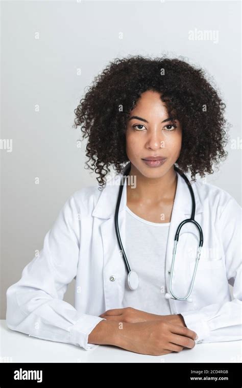 portrait of an attractive afro american doctor with both hands on the top of a white desk ...