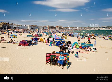 People on the crowded busy seaside beach on a hot summer day, Weymouth beach, Dorset, England ...