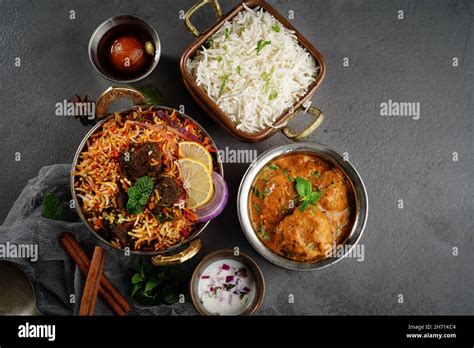 Indian veg non veg meal thali - mutton biryani, raita, malai kofta, basmati rice, and gulab ...