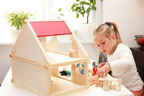 young caucasian girl playing with doll house in playroom during play ...