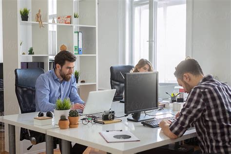 "A Group Of People Sitting At Their Desks Working On The Computers In ...