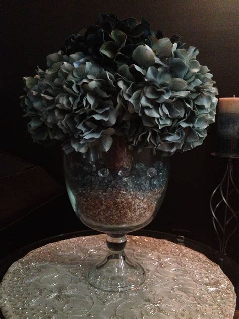 Light teal and dark teal flowers in a vase. I put a skinny vase in the middle of the large vase ...