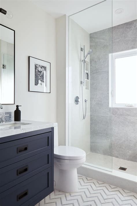 Glass shower with navy blue vanity and chevron tile floor #bathroominspo # ...