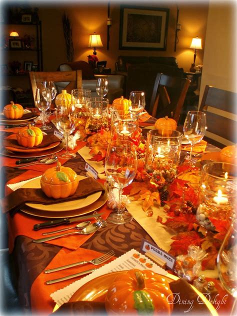 a dining room table set for thanksgiving with pumpkins and candles on the place settings