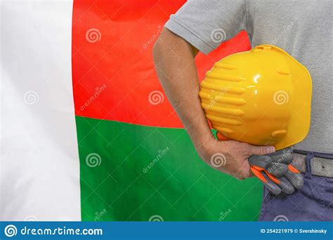 Hand of Worker and Yellow Hard-hat on Background Flag of Madagascar Stock Image - Image of ...