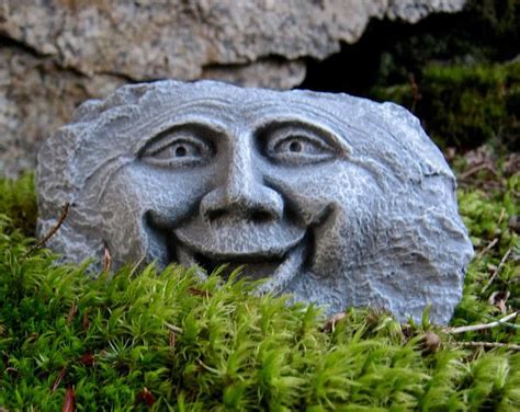 a stone face sitting on top of green moss