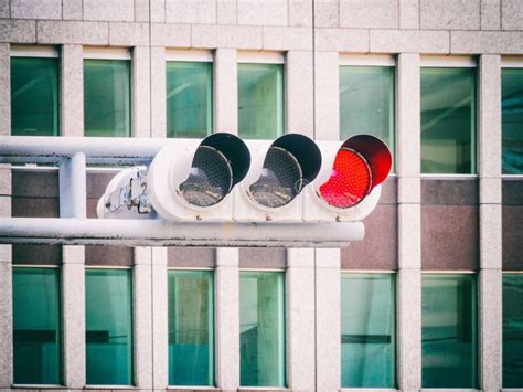 White Horizontal Traffic Light with an Illuminated Red Light on a Pole in Front of a Building ...