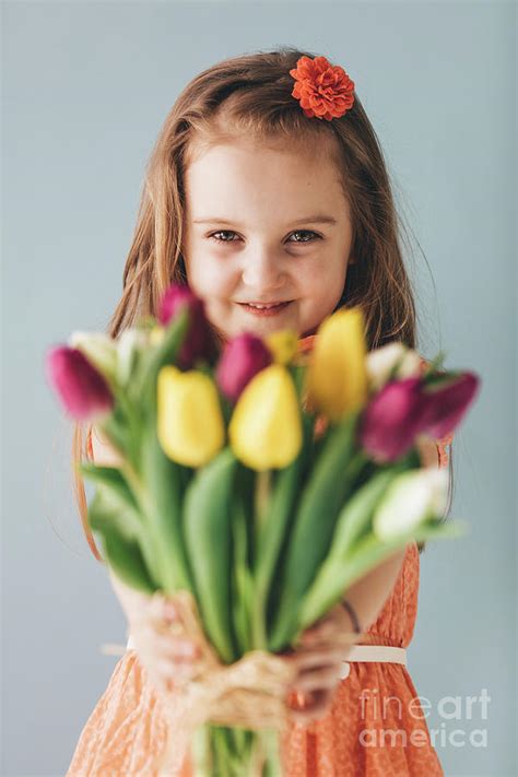 Little girl giving colorful flowers, smiling sincerely Photograph by Michal Bednarek