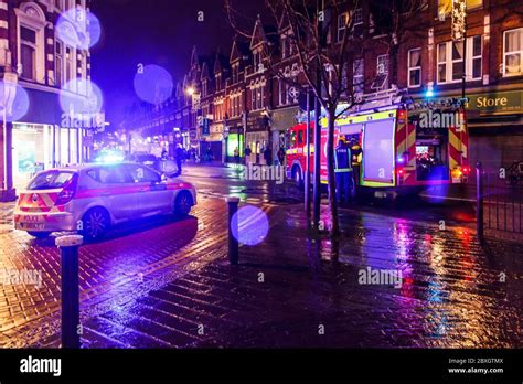 A police car and fire engine attending a vehicle fire on a rainy autumn evening in Crouch End ...
