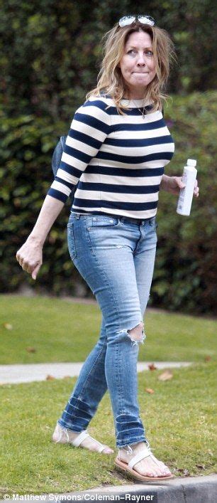 a woman in striped shirt and jeans walking on sidewalk