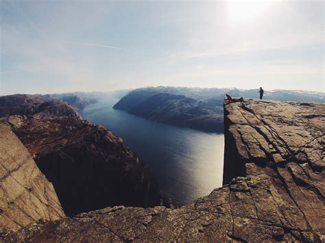 Person standing at the edge of a cliff overlooking river surrounded by mountains HD wallpaper ...