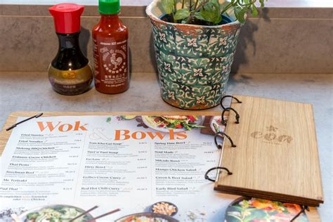 Soy sauce, hot chili sauce, mint and the menu of the coa Wok & Bowl restaurant with wooden ...