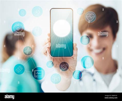 Smiling confident female doctor holding a touch screen smartphone with network of medical icons ...