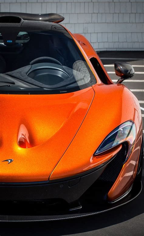 an orange sports car is parked in a parking lot with its hood up and it's lights on