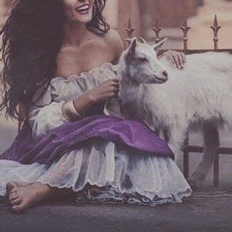 a woman sitting on the ground next to a goat