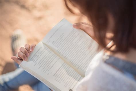 Una mujer joven leyendo un libro. libro en manos de mujer | Foto Premium