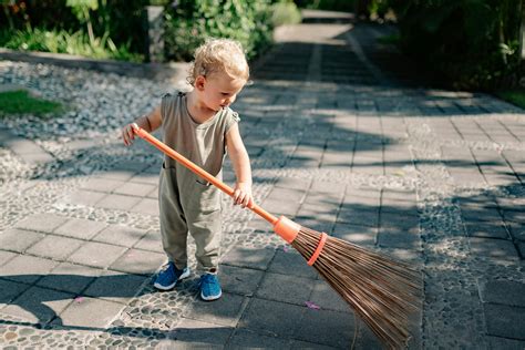 Charming Child Sweeping Concrete Pavement with Broomstick · Free Stock ...