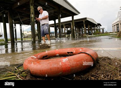 Ben Tucker checks his phone as he surveys the damage around his house from Hurricane Ida ...