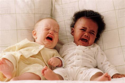 Two babies crying on a couch - Stock Photo - Dissolve