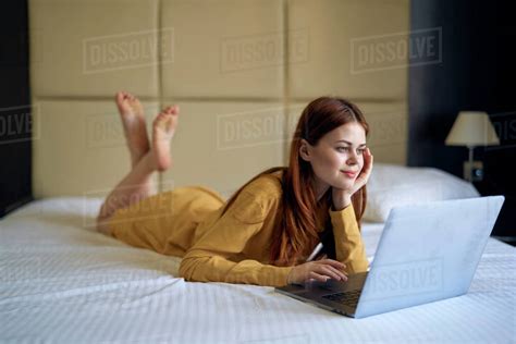 Caucasian woman laying on bed using laptop - Stock Photo - Dissolve