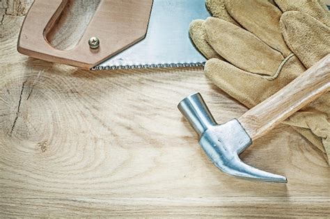 Premium Photo | Claw hammer safety gloves stainless hacksaw on wooden board construction concept