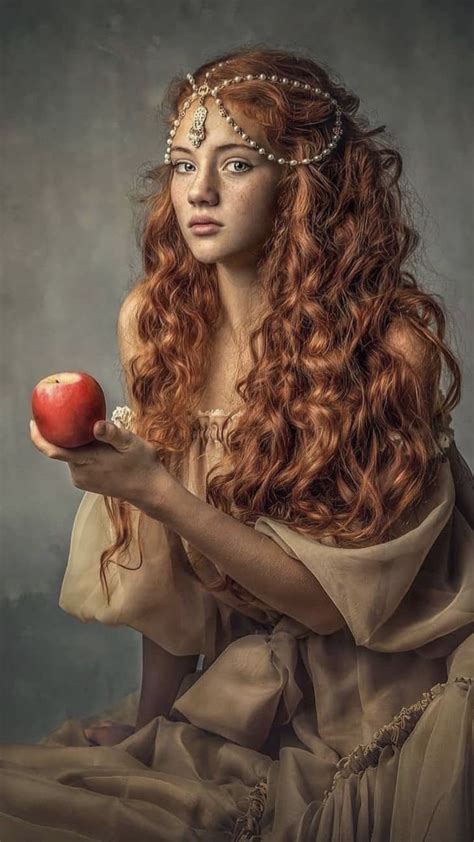 a woman with long red hair holding an apple
