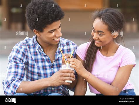 Teenagers drinking milkshake outdoors flirting with each other Stock Photo - Alamy